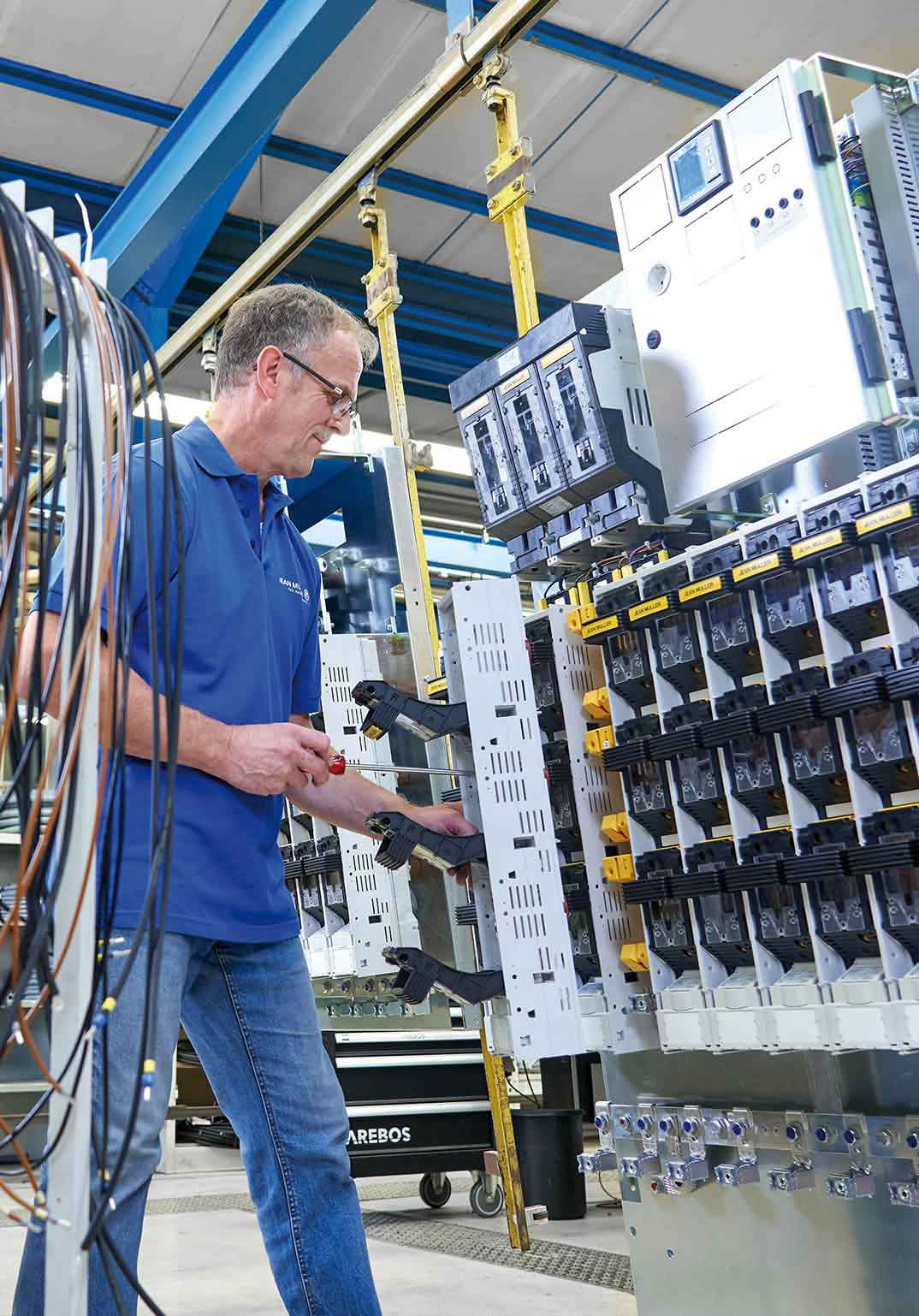 Mann in blauem Hemd, der in einem technischen Umfeld arbeitet, mit Fokus auf Gehäusetechnik und Verteilungen.